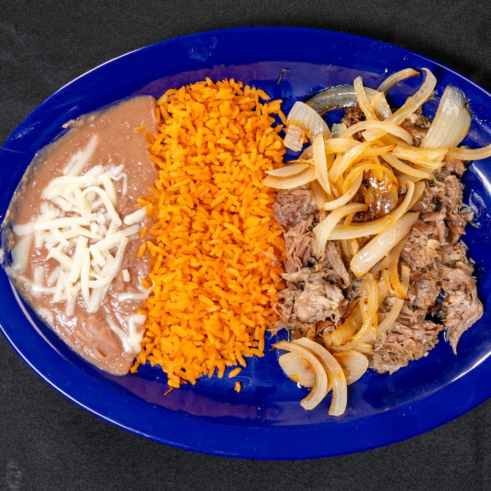 Blue plate of orange rice, refried beans topped with cheese, and shredded beef with sautéed onions.