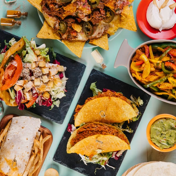 Overhead view of Rio Burritos' Mexican feast: nachos, tacos, burrito, salad, fajitas, guacamole, and sour cream.